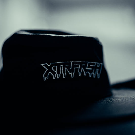 Black bucket hat with white XTRFRSH embroidery (close up).