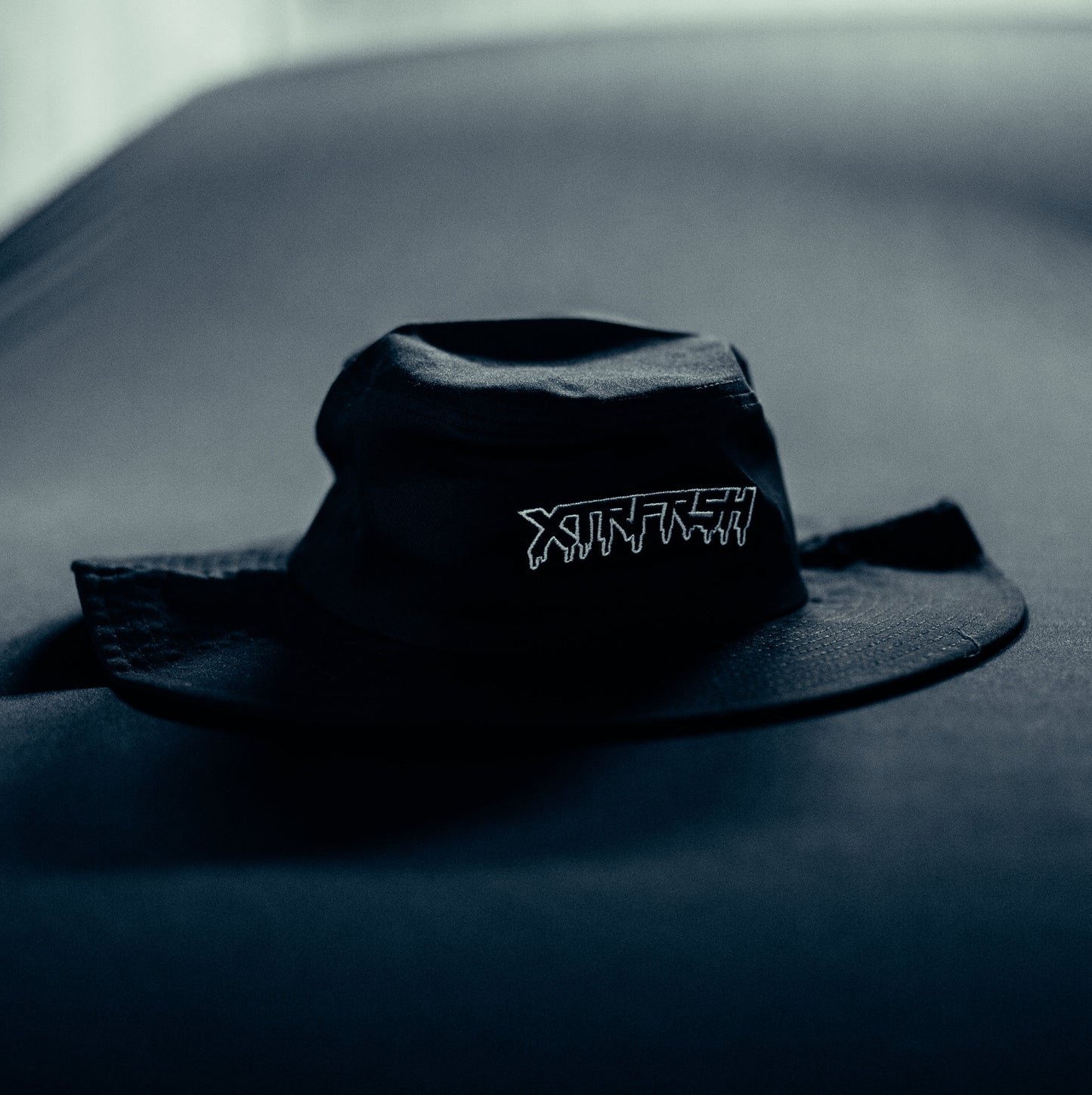 Black bucket hat with white XTRFRSH embroidery.